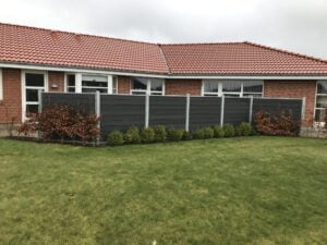 Rød murstenshus med græsplæne og hegn