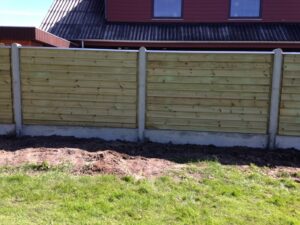 Træhegn foran hus med græsplæne