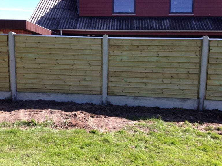 Træhegn foran hus med græsplæne