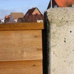 Træ- og betonhegn med huse i baggrunden